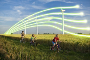 Children Cycling Past Wind Turbines